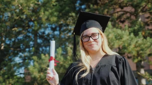 Портрет счастливой выпускницы в мантии и кепке — стоковое видео