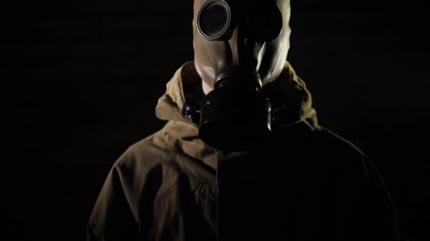 Vippebilde av en mann i beskyttelsesdrakt og gassmaske på svart bakgrunn – stockvideo