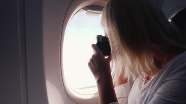 Een passagier van het vliegtuig maakt foto 's van het uitzicht vanuit de patrijspoort — Stockvideo
