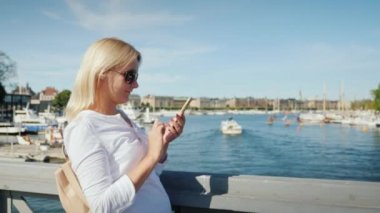 Bir kadın Stockholm, İsveç 'e bakan bir köprüde akıllı telefon kullanıyor.