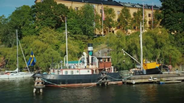 У берега пришвартована старая баржа на фоне многоквартирных домов в Стокгольме — стоковое видео