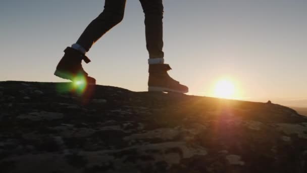 Las piernas caminan en el borde de la tierra del cielo y el sol. Senderismo en las montañas de Noruega — Vídeo de stock