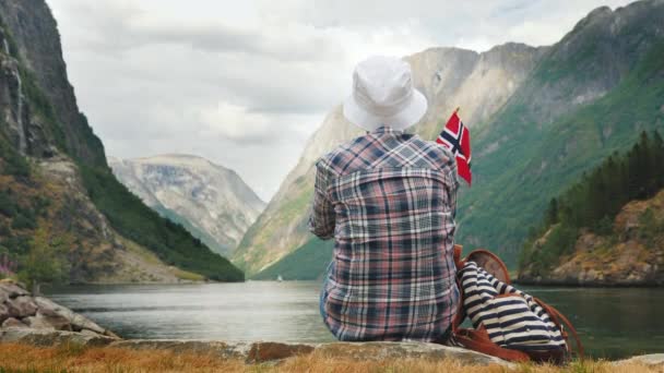 Turisztikai hátizsák és zászló Norvégia csodálja grandiózus fjord — Stock videók