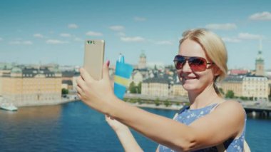 İsveç bayrağı taşıyan kadın Stockholms şehir sınırına karşı kendi fotoğraflarını çekiyor. İskandinavya konseptinde turizm