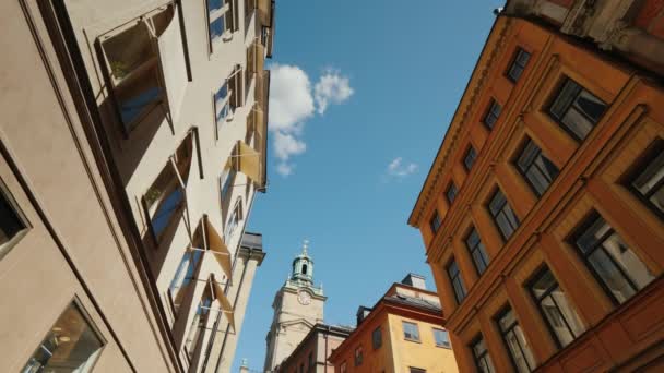 Lage hoek brede schot naar St Nicholas-Storkyrkan klokkentoren in Stockholm. Uitzicht door een smalle straat met oude huizen — Stockvideo