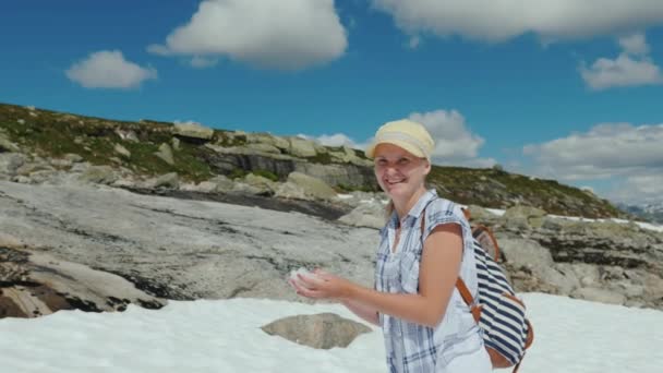 Uma mulher joga uma bola de neve - joga com neve em um dia de verão. Natureza e clima Novegia Concept — Vídeo de Stock