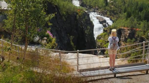 A nő képeket készít a Woringsfossen fenséges vízesésénél Norvégiában. A skandináv természet lenyűgöző szépsége — Stock videók