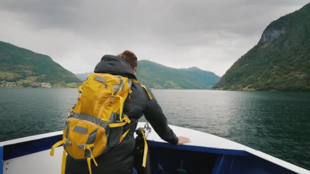 Mann am Bug eines Kreuzfahrtschiffes bewundert den norwegischen Fjord — Stockvideo