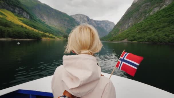 Eine Frau mit norwegischer Flagge am Bug eines Kreuzfahrtschiffes. Reisen durch die Fjorde — Stockvideo