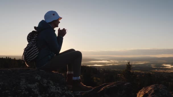 En kvinnlig resenär dricker en varm drink på toppen av berget. Vinna och erövra toppen — Stockvideo