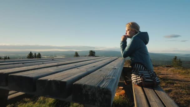 Одинокая женщина средних лет сидит за столом высоко в горах и молится . — стоковое видео