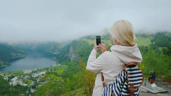 Rear view tourist photographs of a picturesque fjord in Norway. It is worth on a popular photographic object - a flying cliff — Stock Photo, Image