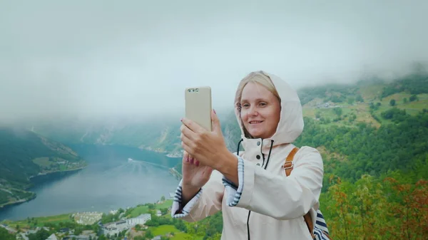 Un turista feliz es fotografiado en el fondo de un pintoresco fiordo en Noruega. Vale la pena en un objeto fotográfico popular - un acantilado volador — Foto de Stock