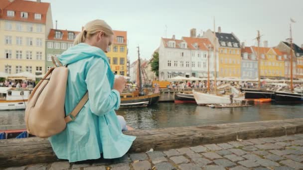 Frau benutzt Smartphone auf Hintergrund Nyhavn Kanal, vor dem Hintergrund der berühmten bunten Häuser. — Stockvideo
