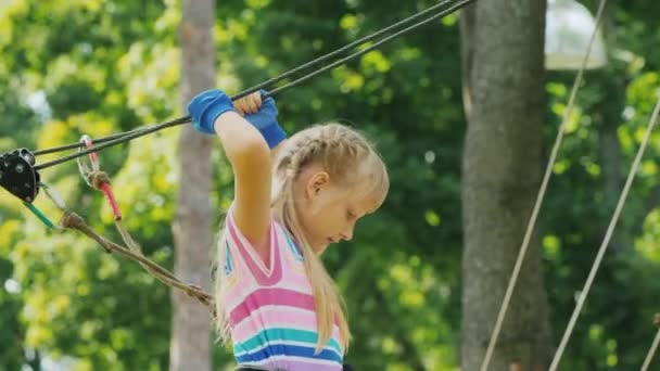 A menina caminha sobre as cordas acima do solo, usa uma corda de segurança — Vídeo de Stock