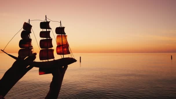 Denizin arka planında oyuncak bir yelkenli taşıyan adam, seyahat ve keşif konsepti — Stok video