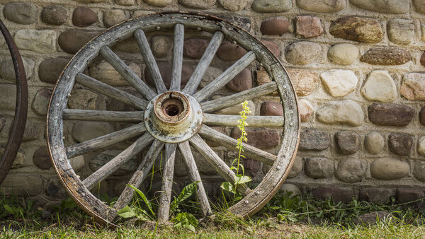 Old cartwheel by the stone wall of an old building