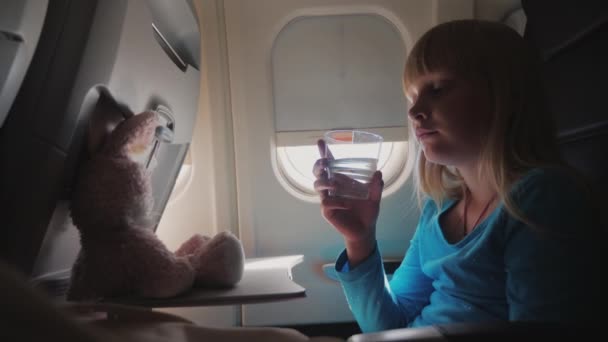 A girl drinks water in the cabin of the plane — 비디오