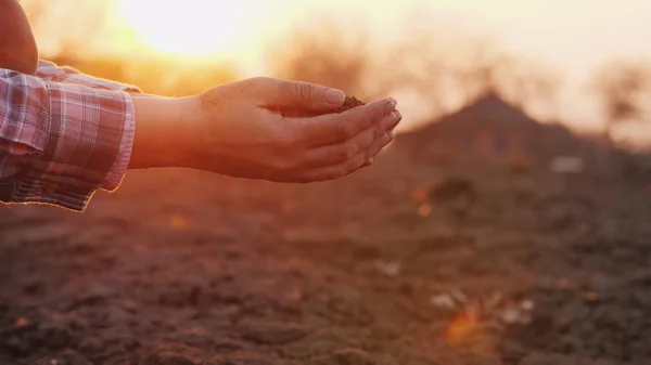 農夫は日没時に手の中の土を見る. — ストック写真