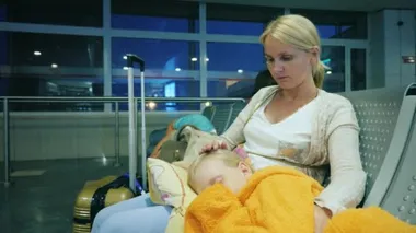 Bir kadın onun kucağına havaalanında terminalde otururken, uyku kız okşayarak. Uçuş gecikme kavramı