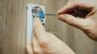 Electrician mounts infrared motion sensor for alarm system