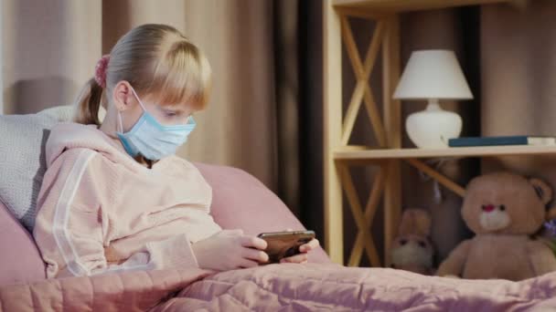 Dziewczyna w bandażu bawi się na smartfonie. Koncepcja kwarantanny i korzeni w domu — Wideo stockowe