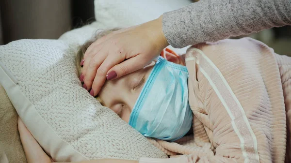 Matka kładzie rękę na czole śpiącego dziecka, sprawdza temperaturę — Zdjęcie stockowe