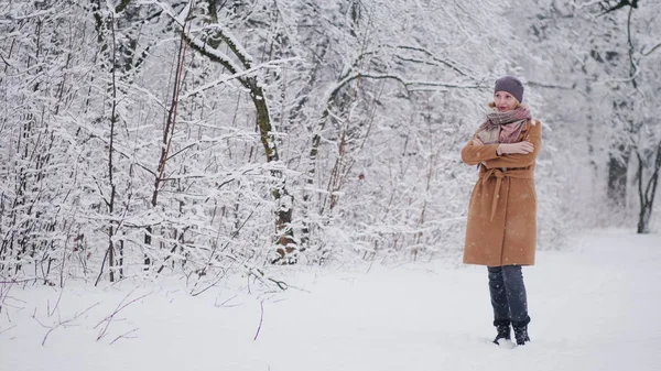 En kvinna står i en vinterpark och beundrar snön. — Stockfoto