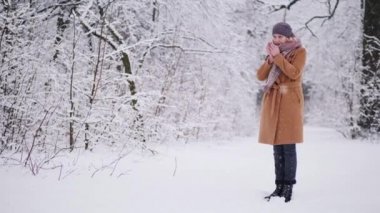 A woman drinks hot tea in the winter forest