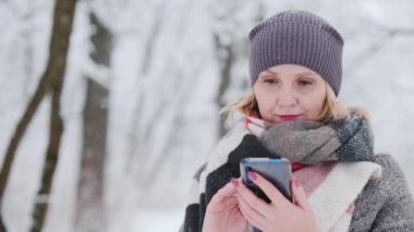 Young woman uses smartphone in snow park