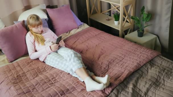 Blick von oben: Teenagermädchen benutzt Smartphone im Schlafzimmer — Stockvideo
