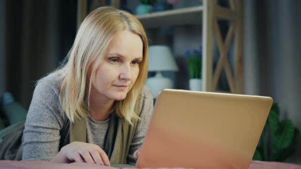 Aantrekkelijke vrouw van middelbare leeftijd werkt met laptop in haar kamer — Stockvideo