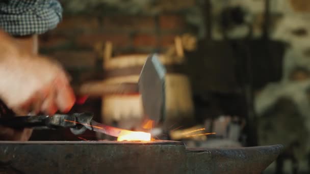 Egy kovács kovácsműhelyben dolgozik, az üllő és a forró, vörös tuskó közelségében, amin a kalapács ver. — Stock videók