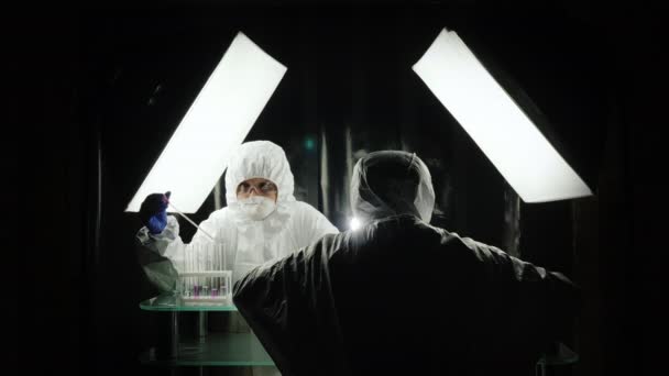 Két tudós dolgozik a laborban védőruhában. — Stock videók