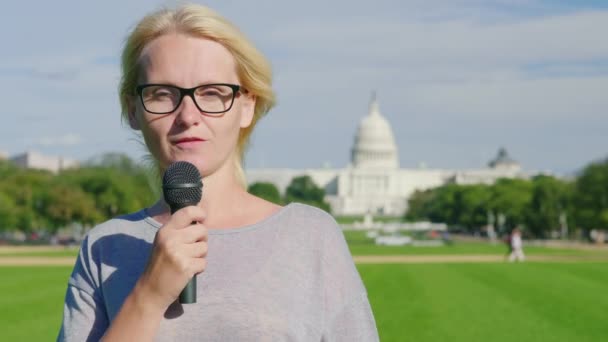 A young female reporter tells the news in a microphone against the backdrop of the Capitol Building in Washington, DC — Stock Video