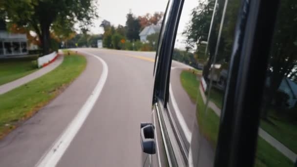 Paseos en auto en una típica ciudad suburbana de los Estados Unidos, la carretera y las casas se reflejan en el lado del coche — Vídeo de stock