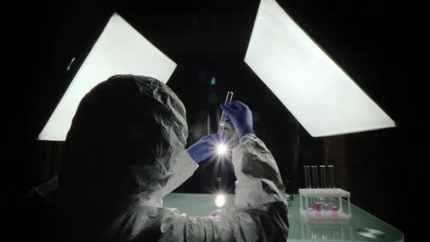 Επιστήμονας κοιτάζει φλασκί, εργάζεται στο εργαστήριο φωτίζεται από προβολείς — Αρχείο Βίντεο