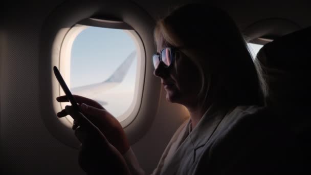 Вид сбоку Молодая женщина читает электронную книгу в полете — стоковое видео