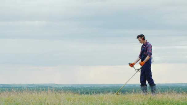 Jeune homme tondre l'herbe avec une tondeuse sur une prairie pittoresque — Video