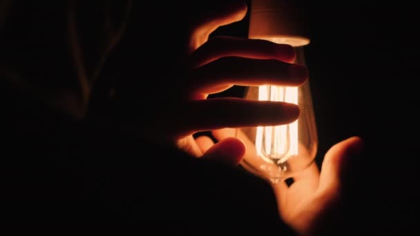 Mens hands near an electric light bulb in the dark — Stock Video