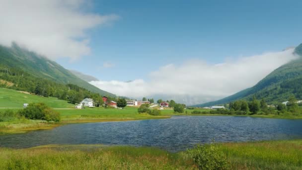 En pittoresk sjö i fjällen och en by i bakgrunden. Norges natur — Stockvideo