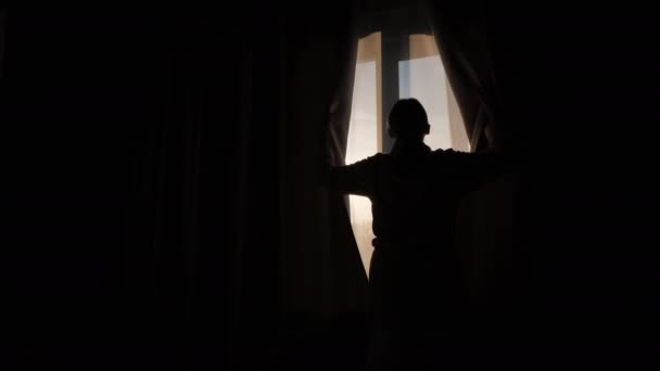 Sylwetka kobiety, rozsuwa zasłony na oknie i raduje się nowym dniem — Wideo stockowe