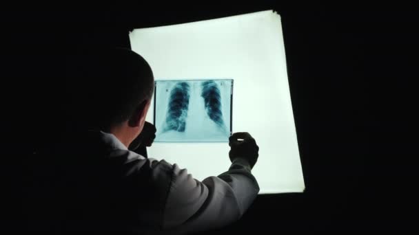 La silueta del médico, estudiando las radiografías de los pacientes — Vídeo de stock