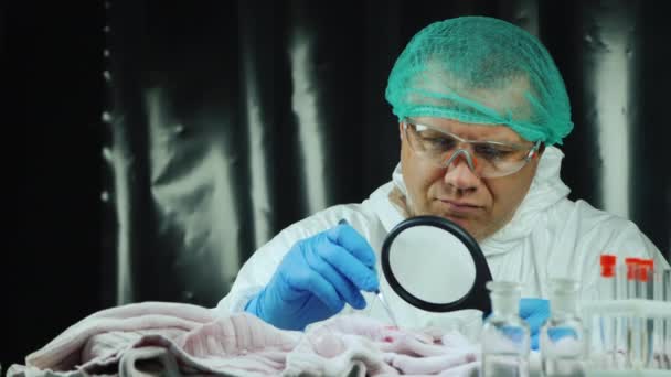 Trabajador de laboratorio masculino examina evidencia en ropa — Vídeo de stock