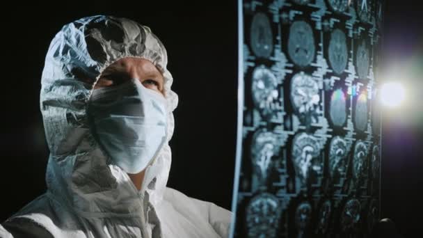 Dokter in beschermende kleding kijkt naar de resultaten van het patiëntenonderzoek — Stockvideo