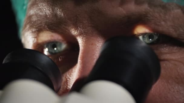 Чоловічий лаборант дивиться в окуляри мікроскопа — стокове відео