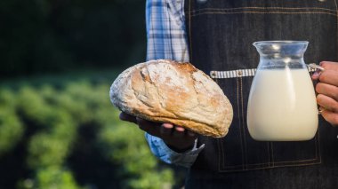 Çiftçi ekmek ve bir sürahi süt tutuyor.