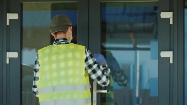 Een koerier met een masker en beschermende handschoenen levert een pakket. Werken bij een pandemie — Stockvideo