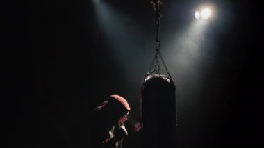 Top View Fighters silueti, spor salonundaki üçlü boks armuduna çarpıyor.
