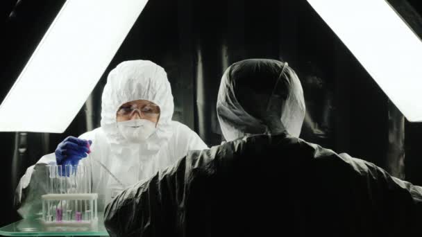 Two lab technicians work in the lab, dressed in protective suits — Stock Video